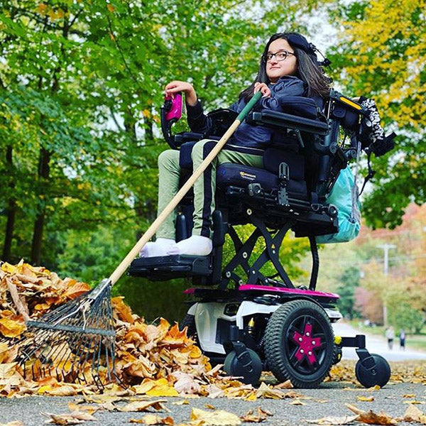 Girl raking leaves in customised power wheelchair